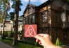 Airbnb logo being held up in front of a house