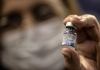 A person holds up a jar of Covid-19 vaccine