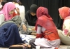 Refugee women in Malaysia seated on the floor doing group work