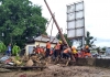 Indonesian workers replacing electricity poles in a flood zone