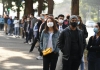 People wearing masks wait in line for a COVID-19 test