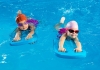 Two children with caps and goggles use kickboards in a swimming pool