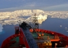 Icebergs and ice sheets can be seen ahead of the bow of an ice-breaker vessel