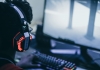 A gamer wearing big headphones plays a game on his computer