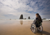 Young woman in a wheelchair on the shore of a rocky beach