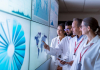 researchers in lab coats confer over information