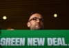 greens leader adam bandt at a lectern saying 'green new deal'