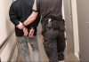 handcuffed prisoner is escorted by a guard
