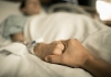 Photo of male patient lying in hospital bed holding hands