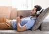 man at home on sofa listening to music with a smartphone