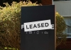 Leased sign covers a for sale sign outside of a residential building