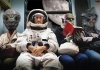 Astronaut and aliens seated in a space bus