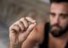 Man holding an ecstasy pill. Focus on the pill
