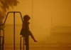Girl on a climbing frame in sunlight filtered through thick bushfire smoke 