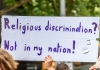 Someone holding a sign saying 'religious discrimination not in my nation'.