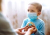 A child wearing a protective sterile medical mask with the parent holding a globe. 
