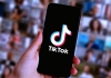 A hand holding a smartphone showing the TikTok app