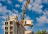 A crane lifts a prefabricated structure onto a building under construction