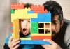 a boy and man looking through the window of a small Lego house