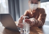 Woman working on a laptop wears protective mask