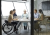 women in a wheelchair in office with colleagues