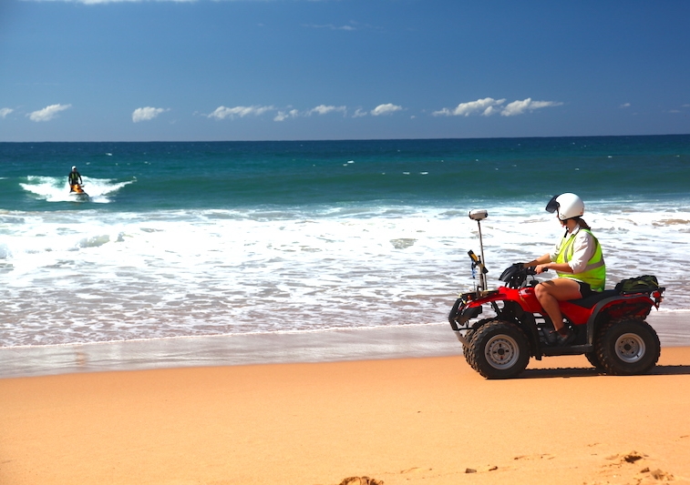UNSW engineer Melissa Bracs on a quad bike with a jetski taking hydrographic soundings in the background.