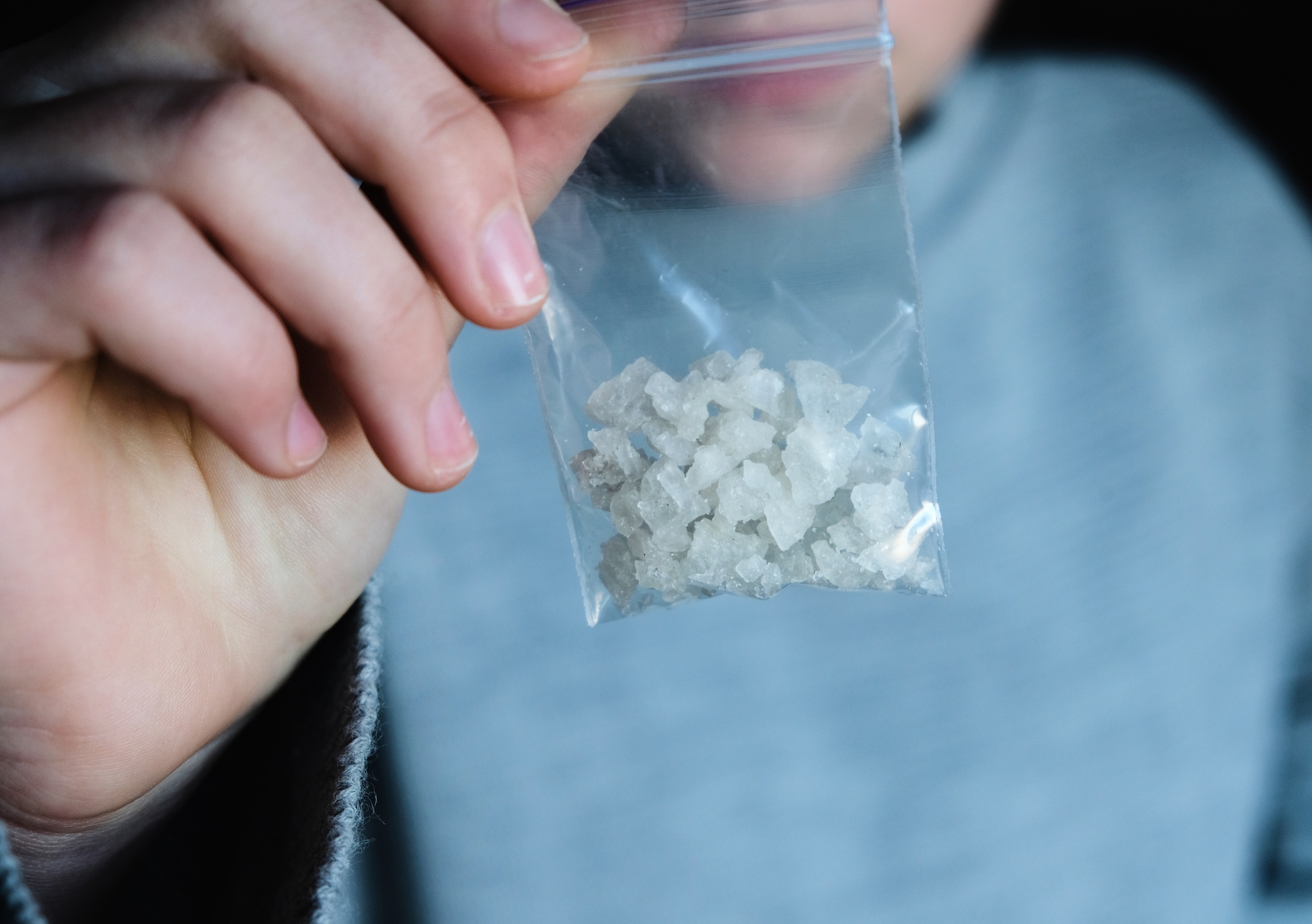 A hand holds a packet with white narcotic. Photo: Shutterstock