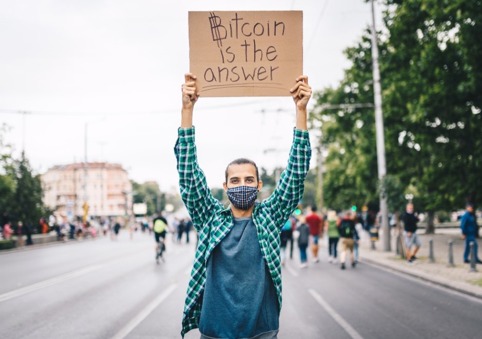 Man holding up sign that reads Bitcoin is the answer.jpg