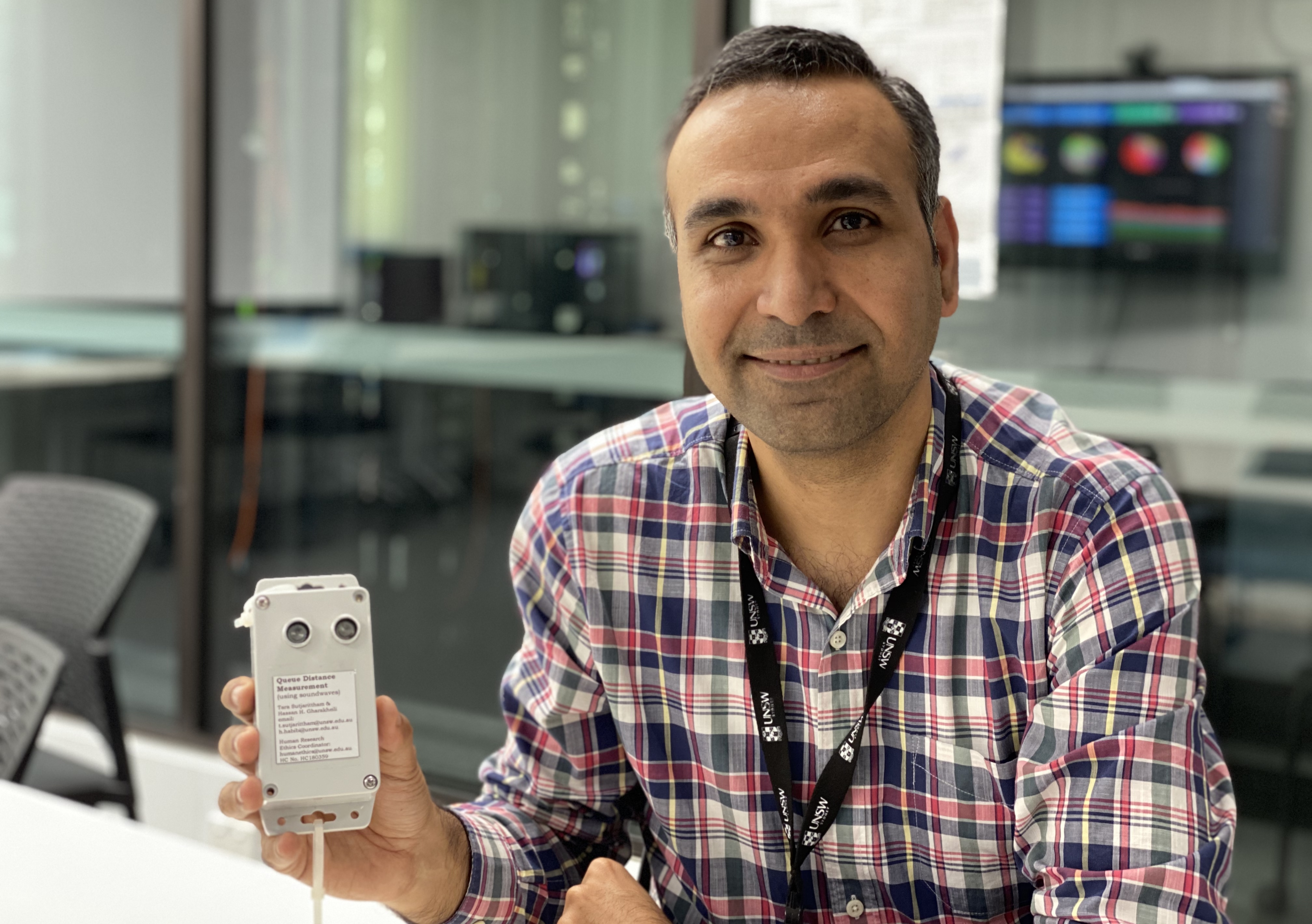 Dr Hassan Habibi Gharakheili with one of the sensors purpose-built to monitor the line length of people queuing for the bus at UNSW. Photo: UNSW