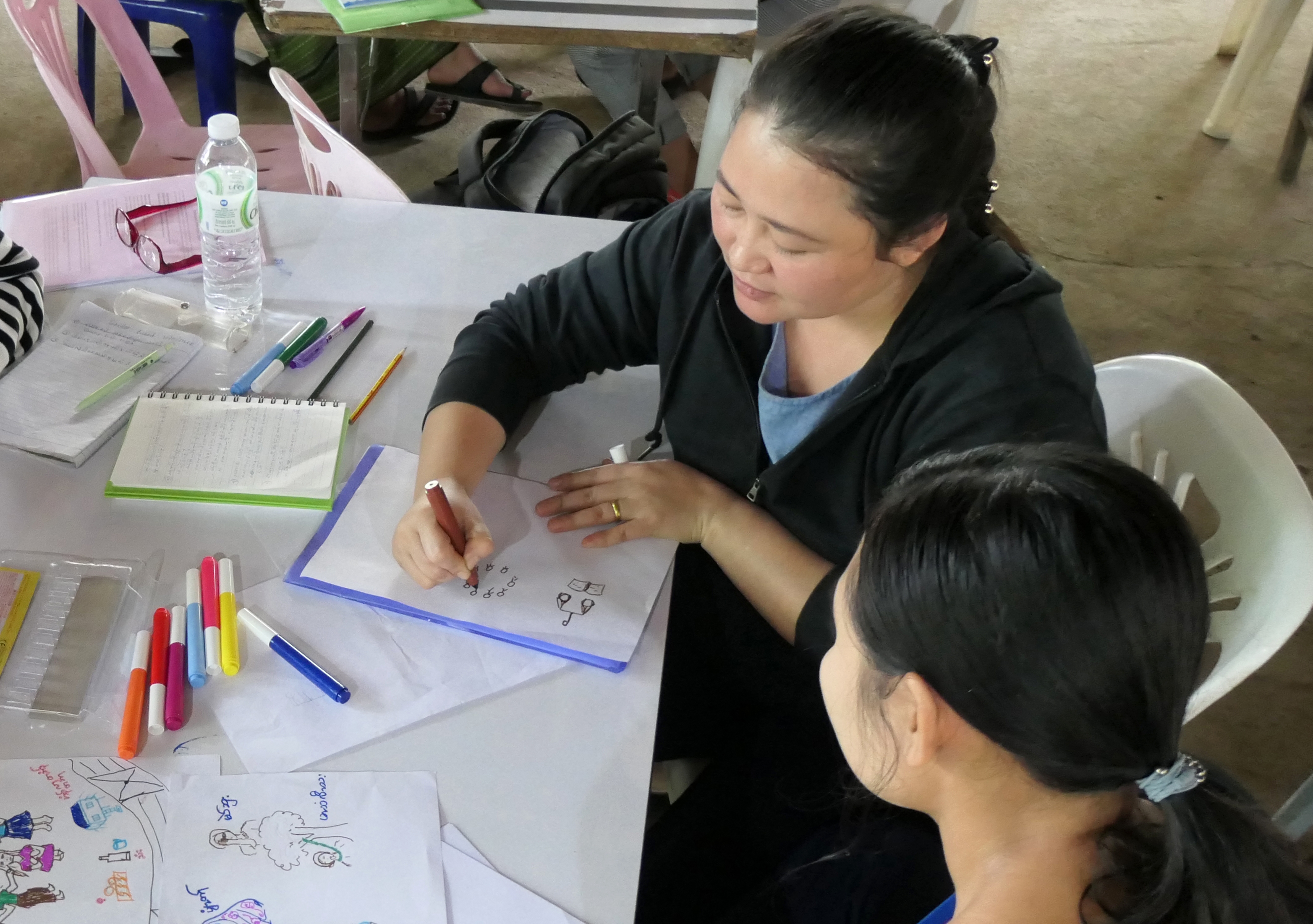Refugee women in Malaysia drawing storyboards seated at a desk