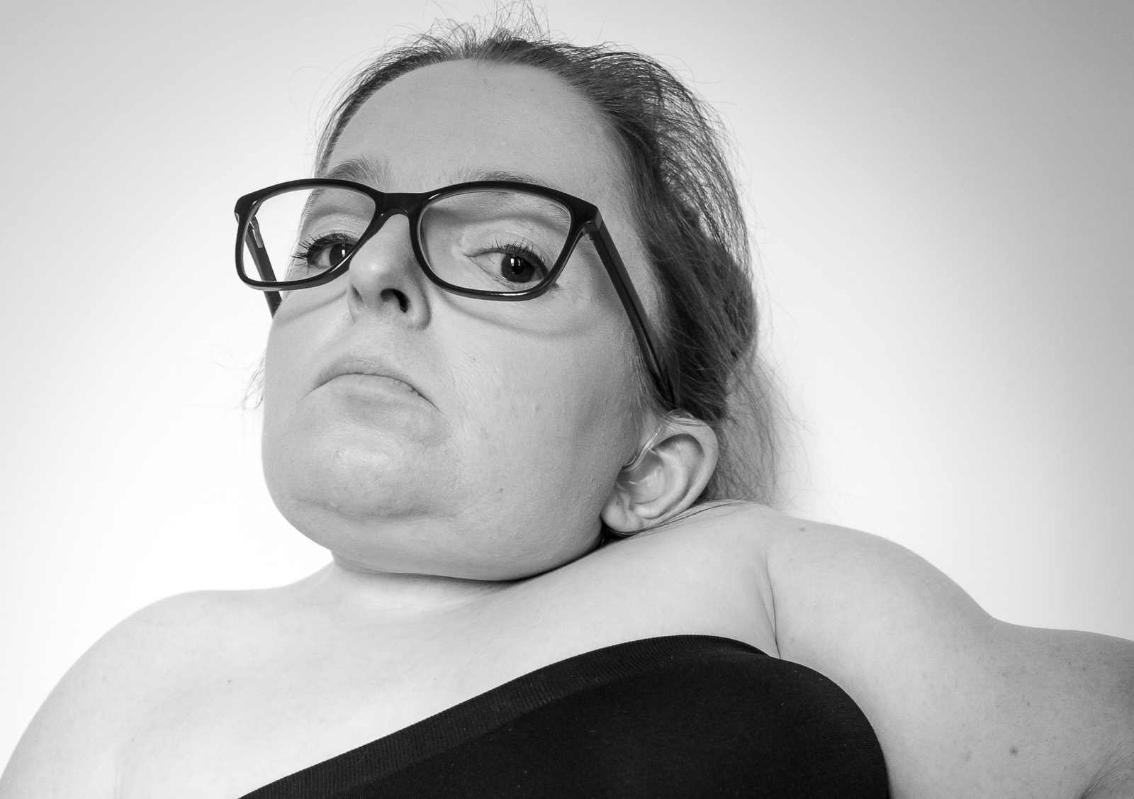 A woman wearing glasses and a strapless top looks into the camera